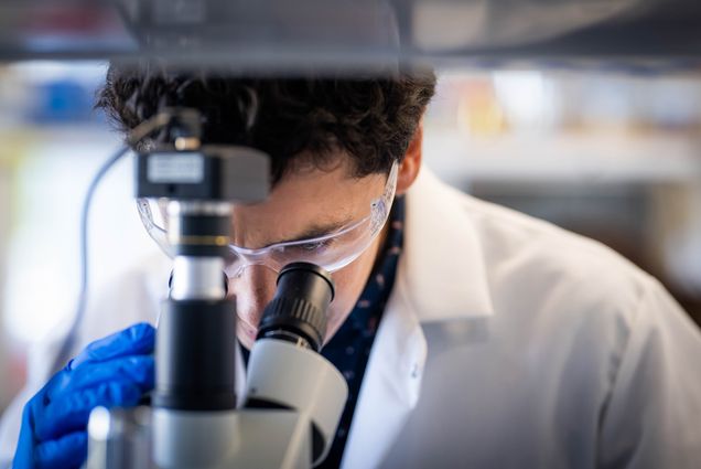 Close-up of biomedical engineer Miguel Jimenez looking into a microscope